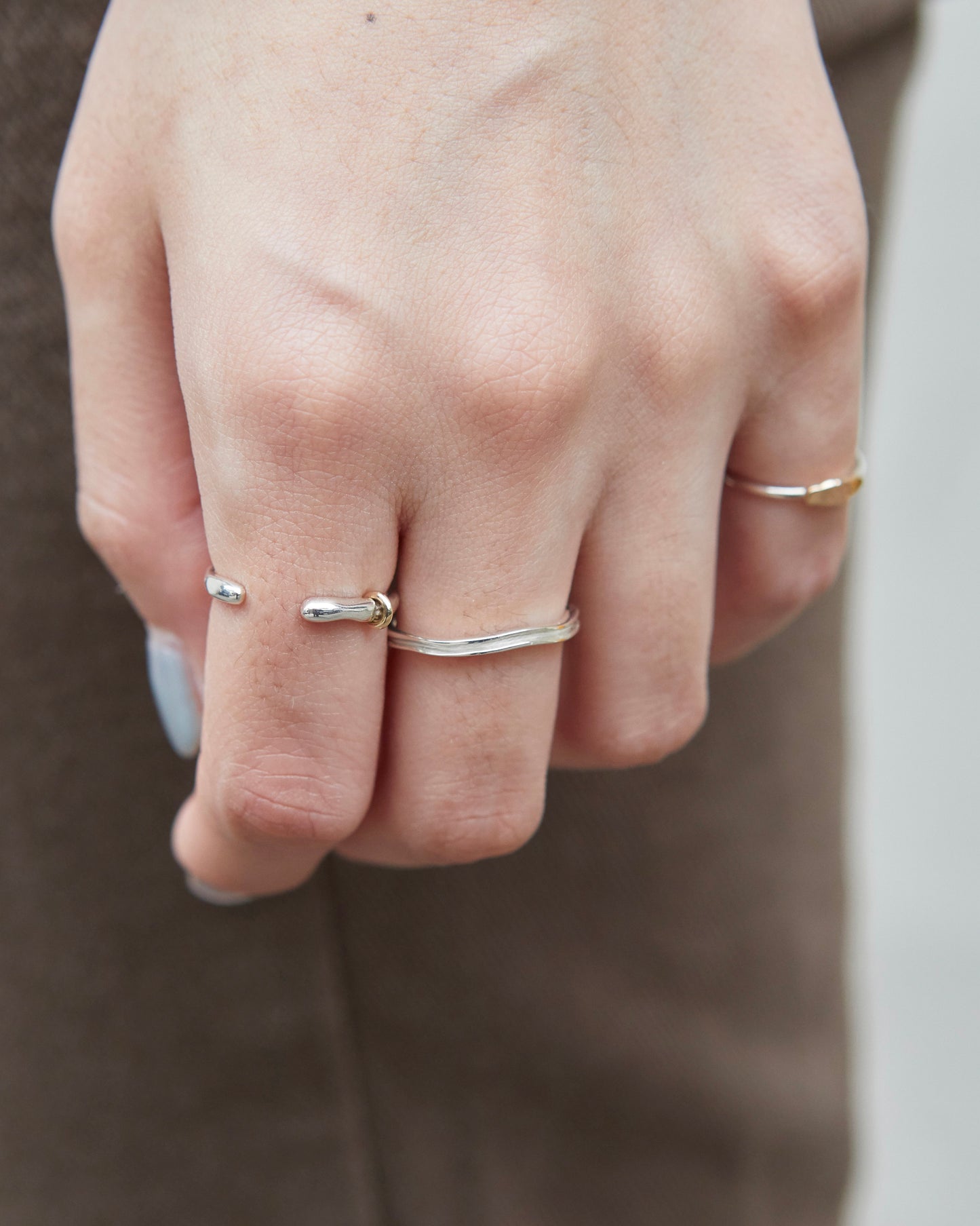 Silver ring with shifting white tone worn on index finger, styled with neutral outfit.