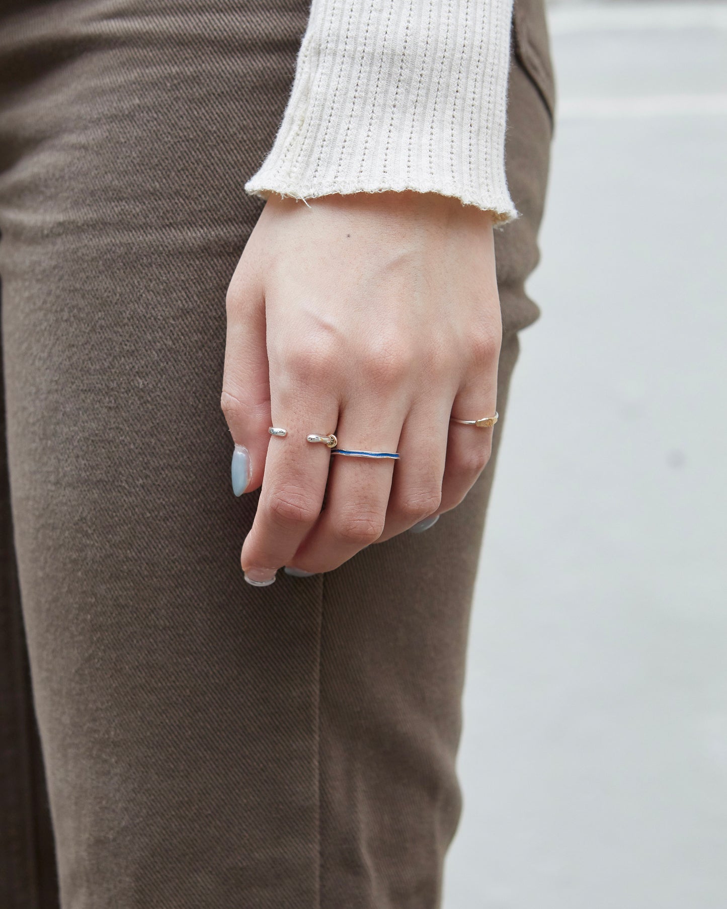 Gold-toned slim ring on middle finger, styled with a thin silver ring with cobalt blue and a cozy ribbed sleeve